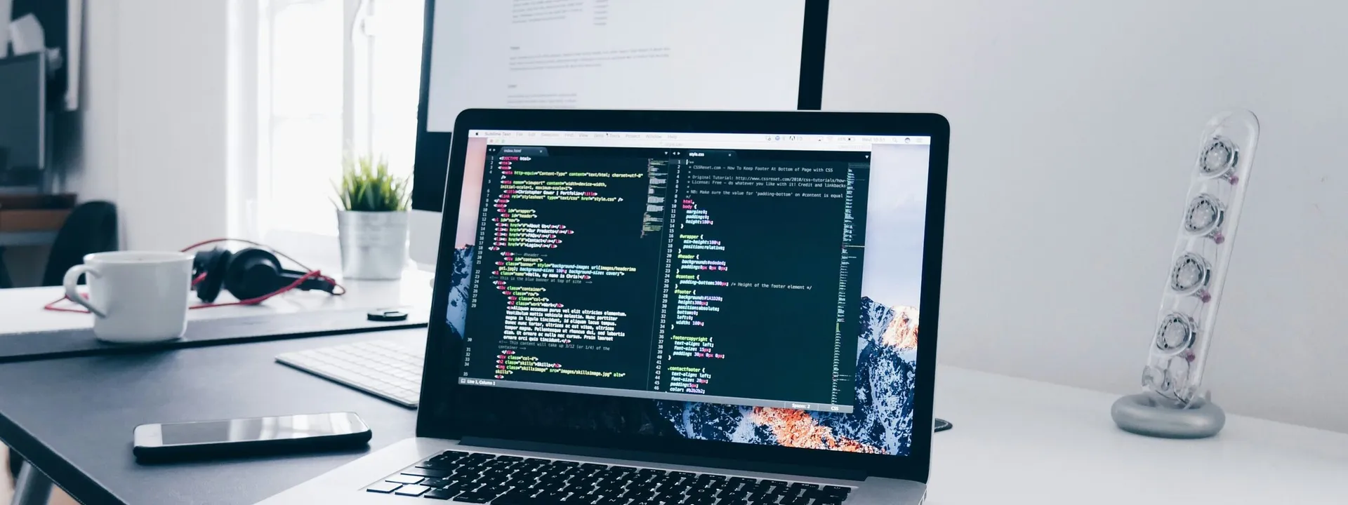 Laptop and monitor on a desk showing software code